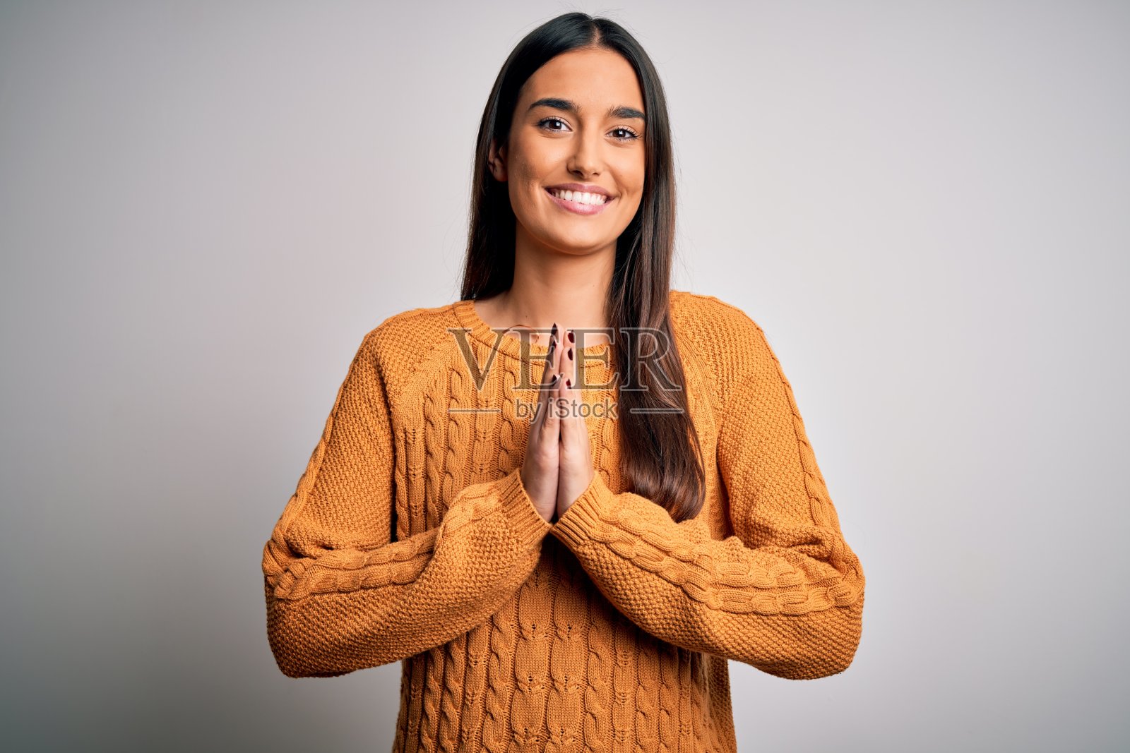 年轻美丽的黑发女人穿着休闲毛衣在孤立的白色背景祈祷与手一起请求宽恕微笑自信。照片摄影图片