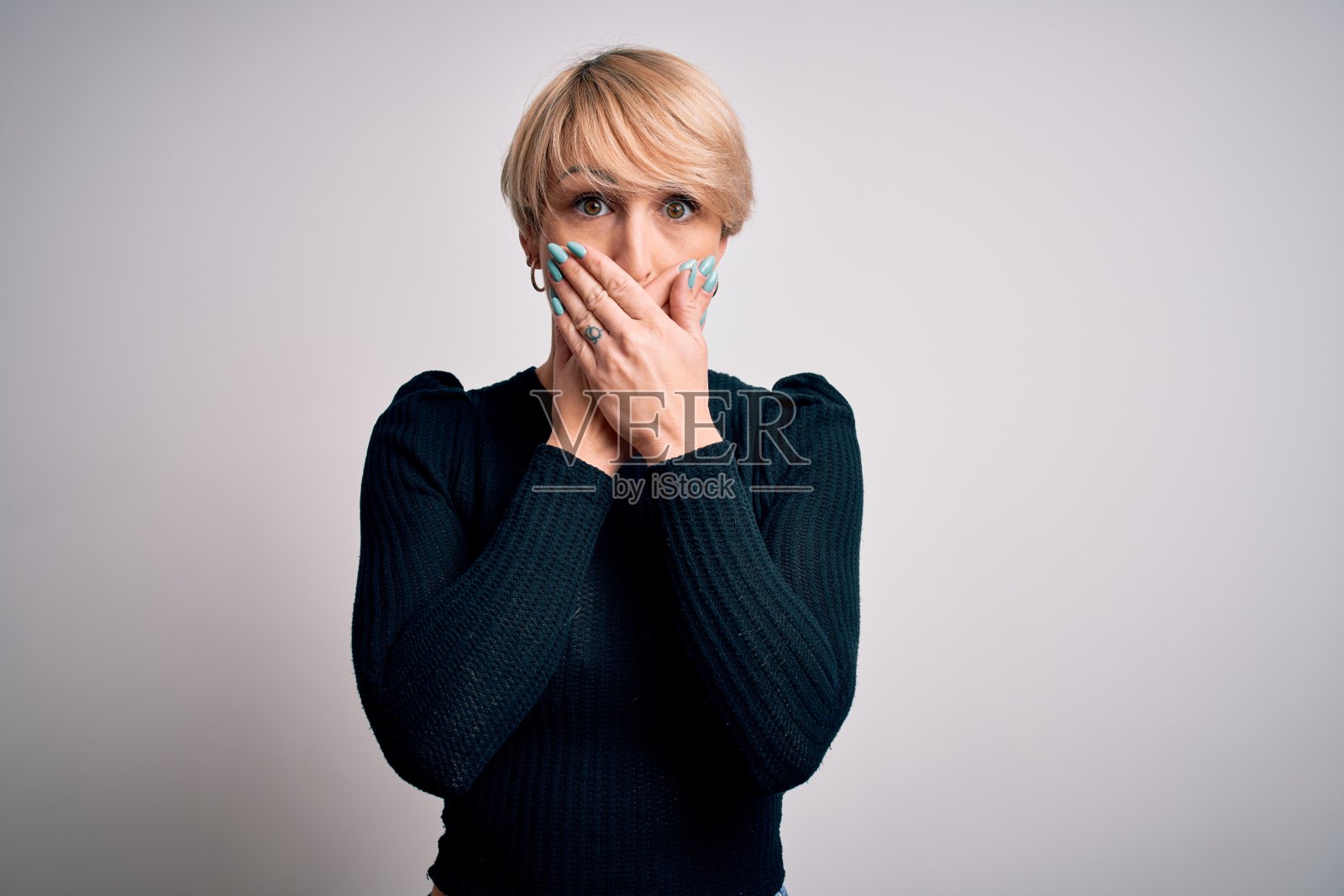 年轻美丽的金发女子与现代短发发型站在孤立的背景震惊掩盖嘴与手的错误。秘密的概念。照片摄影图片