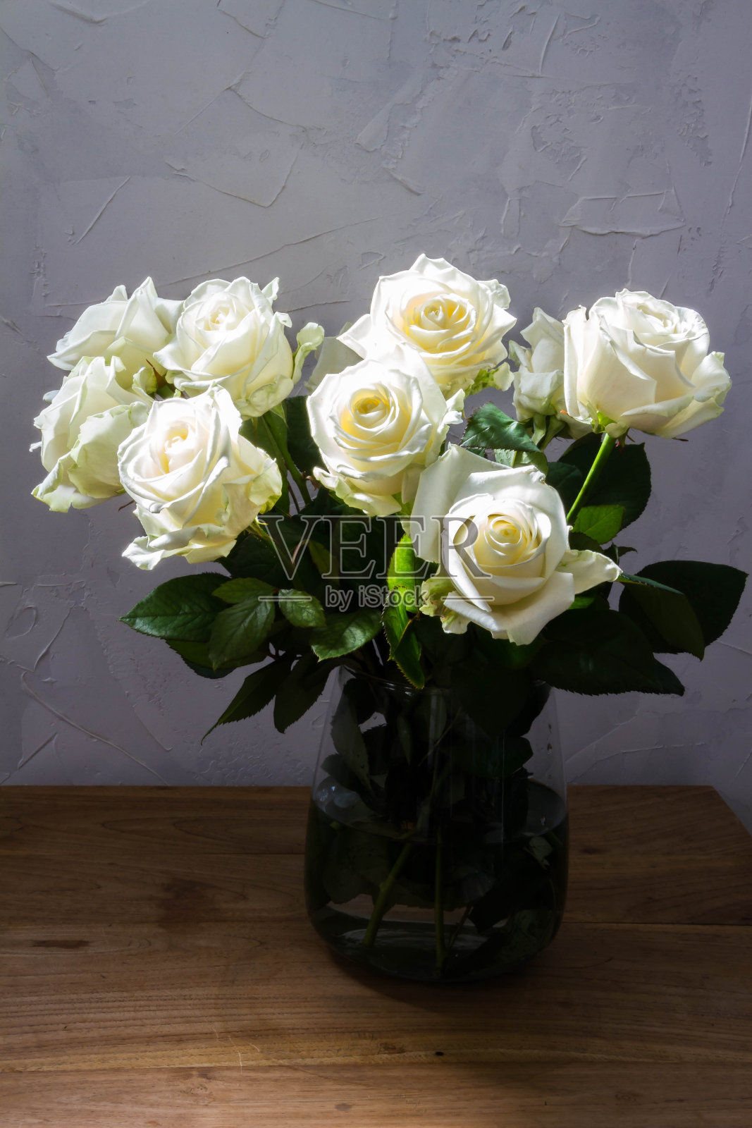 玻璃花瓶里的白玫瑰。照片摄影图片