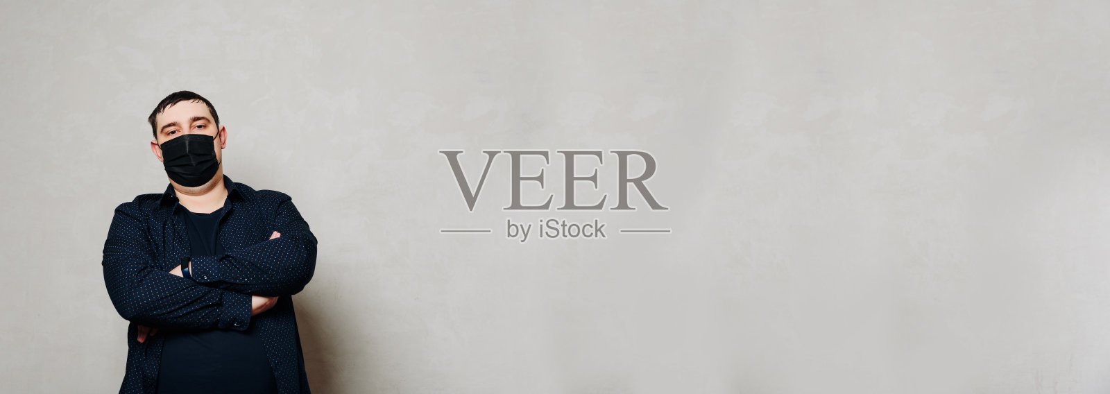 戴黑色口罩的男子,背景为灰色墙壁照片摄影图片