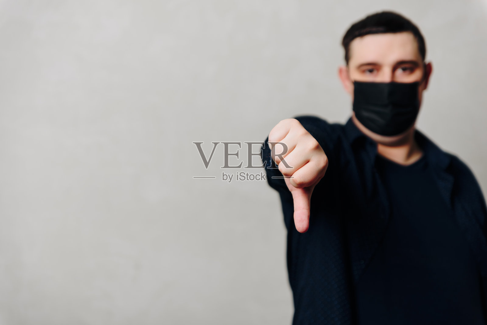 灰色背景下手戴黑色医用口罩的男人点赞照片摄影图片