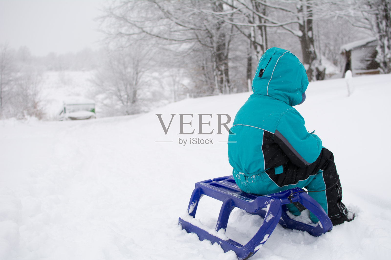 一个孩子坐在雪橇上照片摄影图片