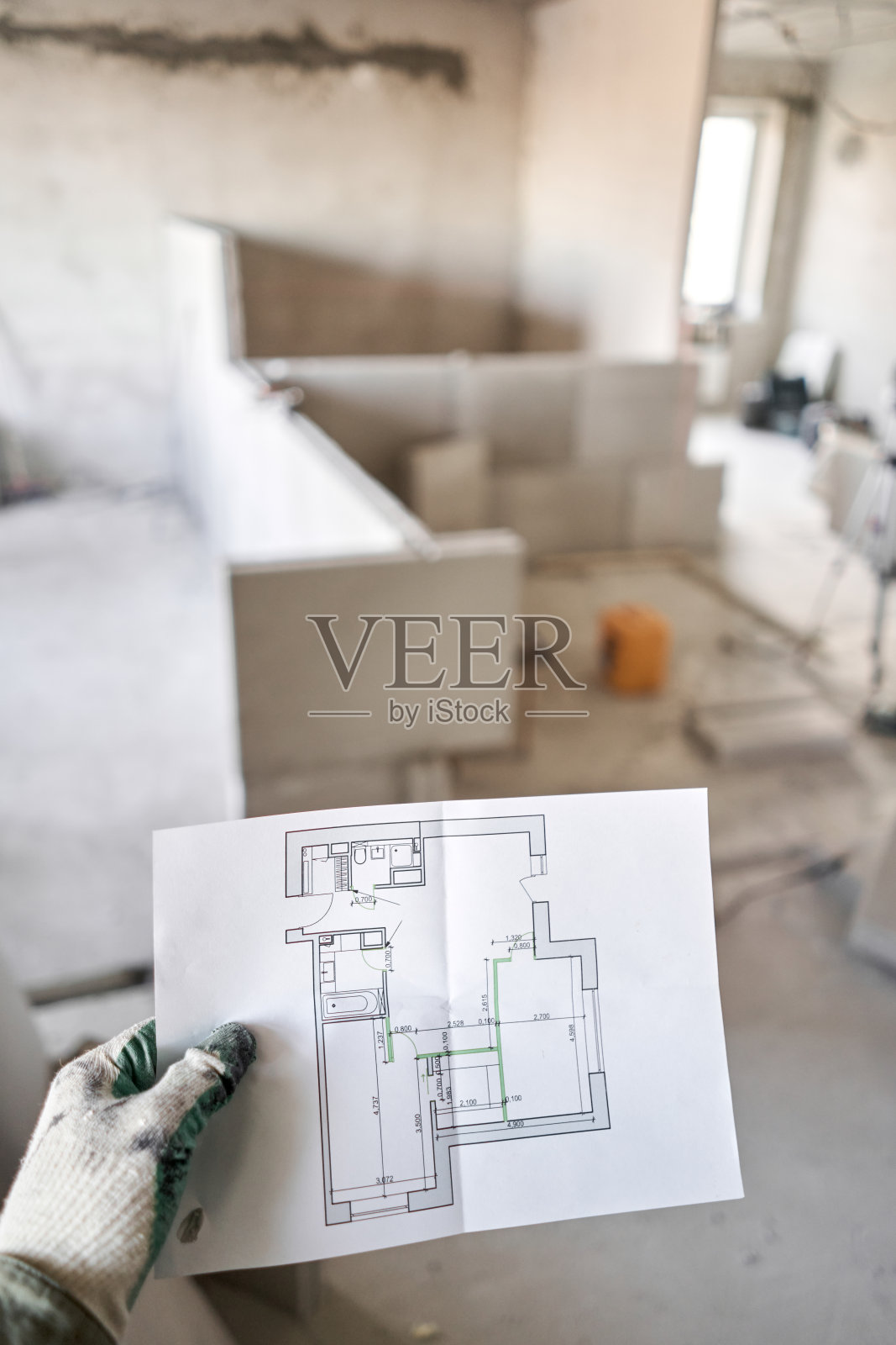 建筑工人手里拿着建筑蓝图。修理或建造新公寓新房子设计或家庭改善的概念。开发公寓项目。照片摄影图片