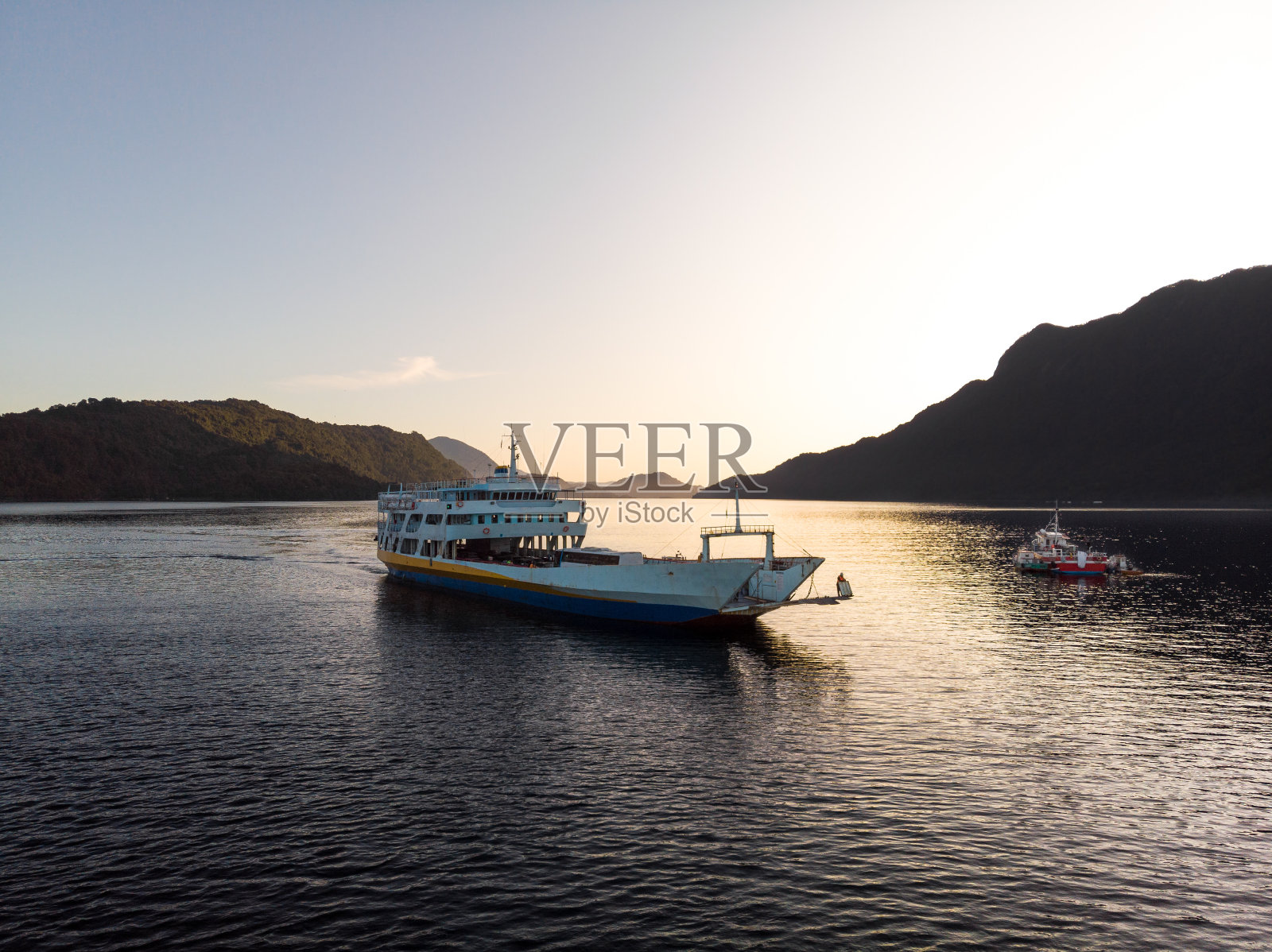 日落时分,渡船驶过智利南部的峡湾照片摄影图片