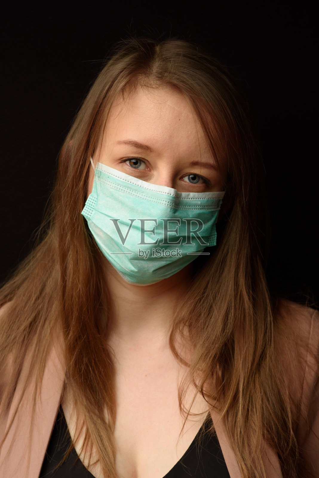 在黑色背景上戴着医用口罩的年轻女孩照片摄影图片