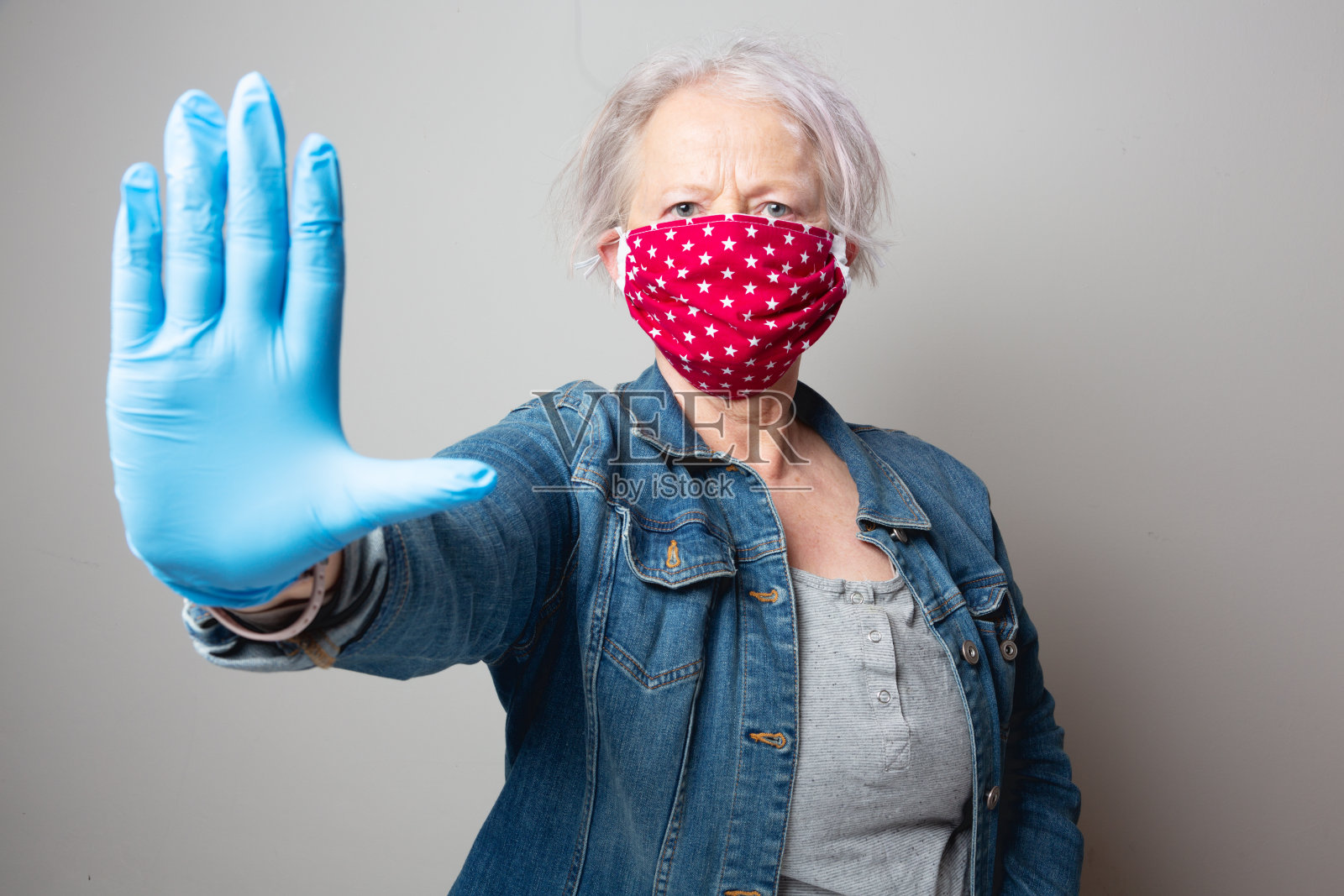 一位戴着防护面罩的妇女的肖像在冠状病毒爆发时使停止标志照片摄影图片