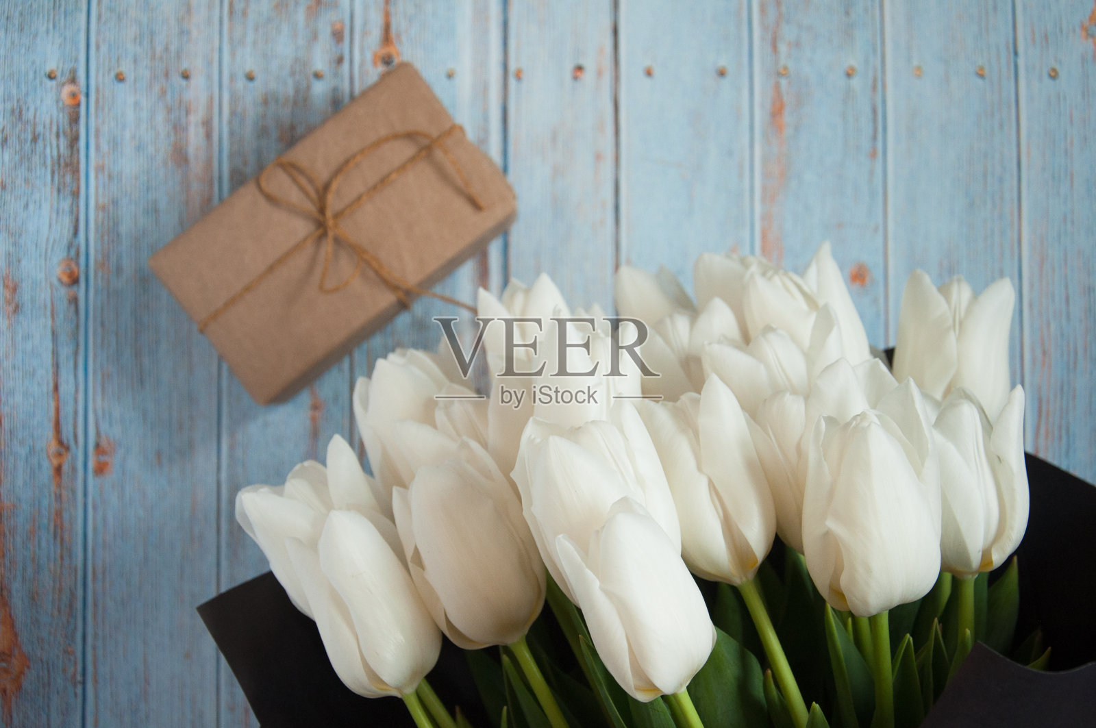 背景用鲜花。一束白色和黄色的郁金香,在木质的蓝色背景上。妇女节、生日、母亲节的礼物。贺卡与鲜花和地方的文字。照片摄影图片