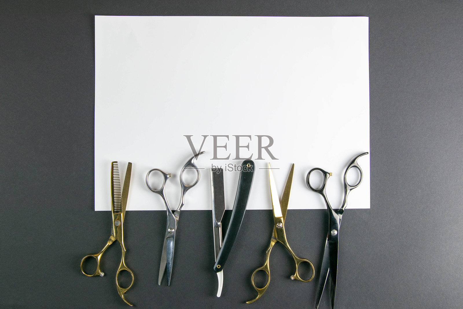 剪刀,理发器,梳子,危险的剃须刀在白色的床单上在黑色的背景。美容的概念照片摄影图片