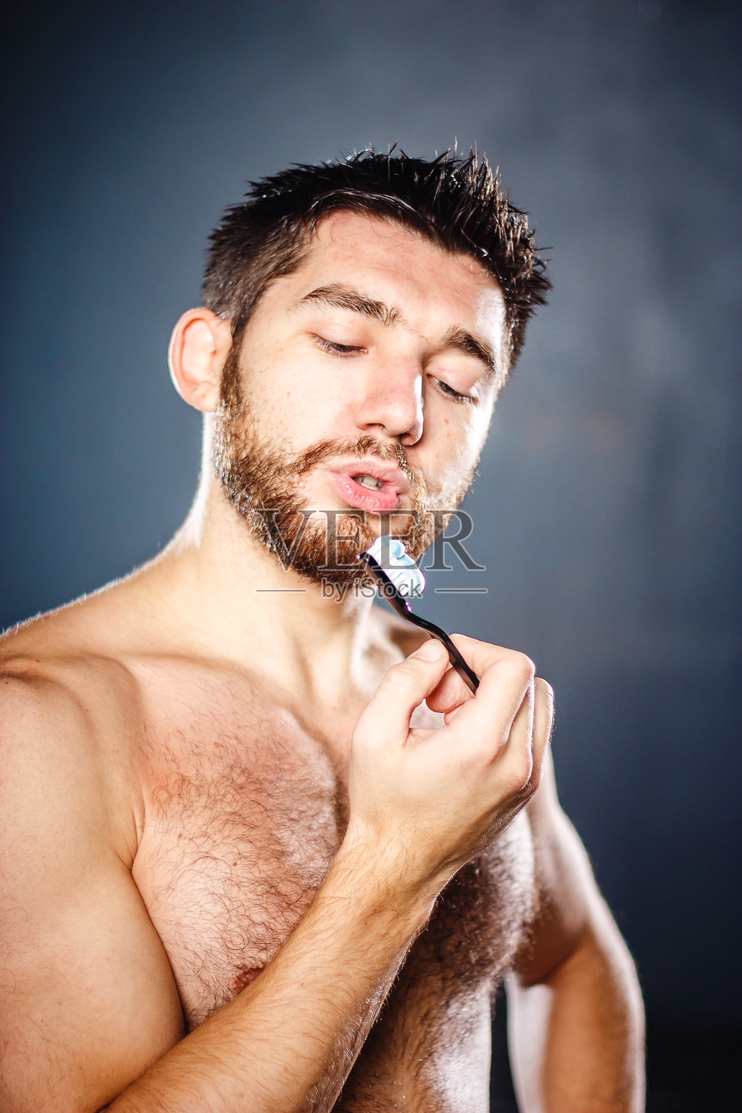 多毛英俊迷人的年轻人正在刷牙照片摄影图片