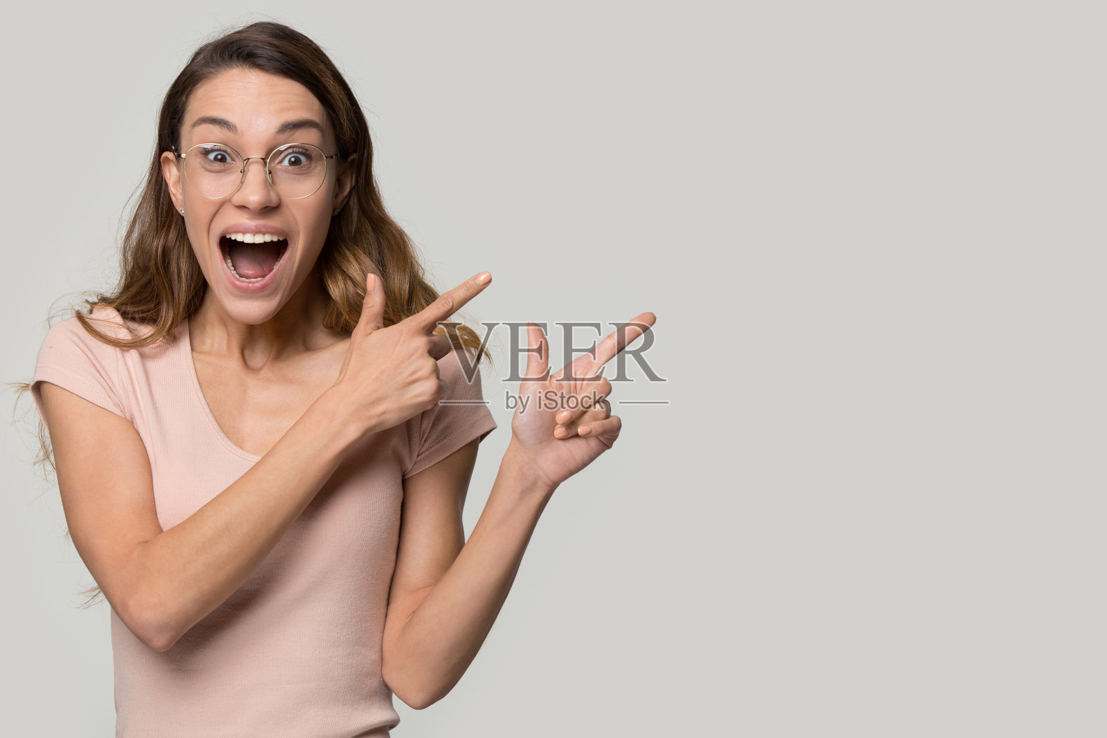 一名戴着眼镜的年轻女子指着复印空间,兴奋而惊讶照片摄影图片