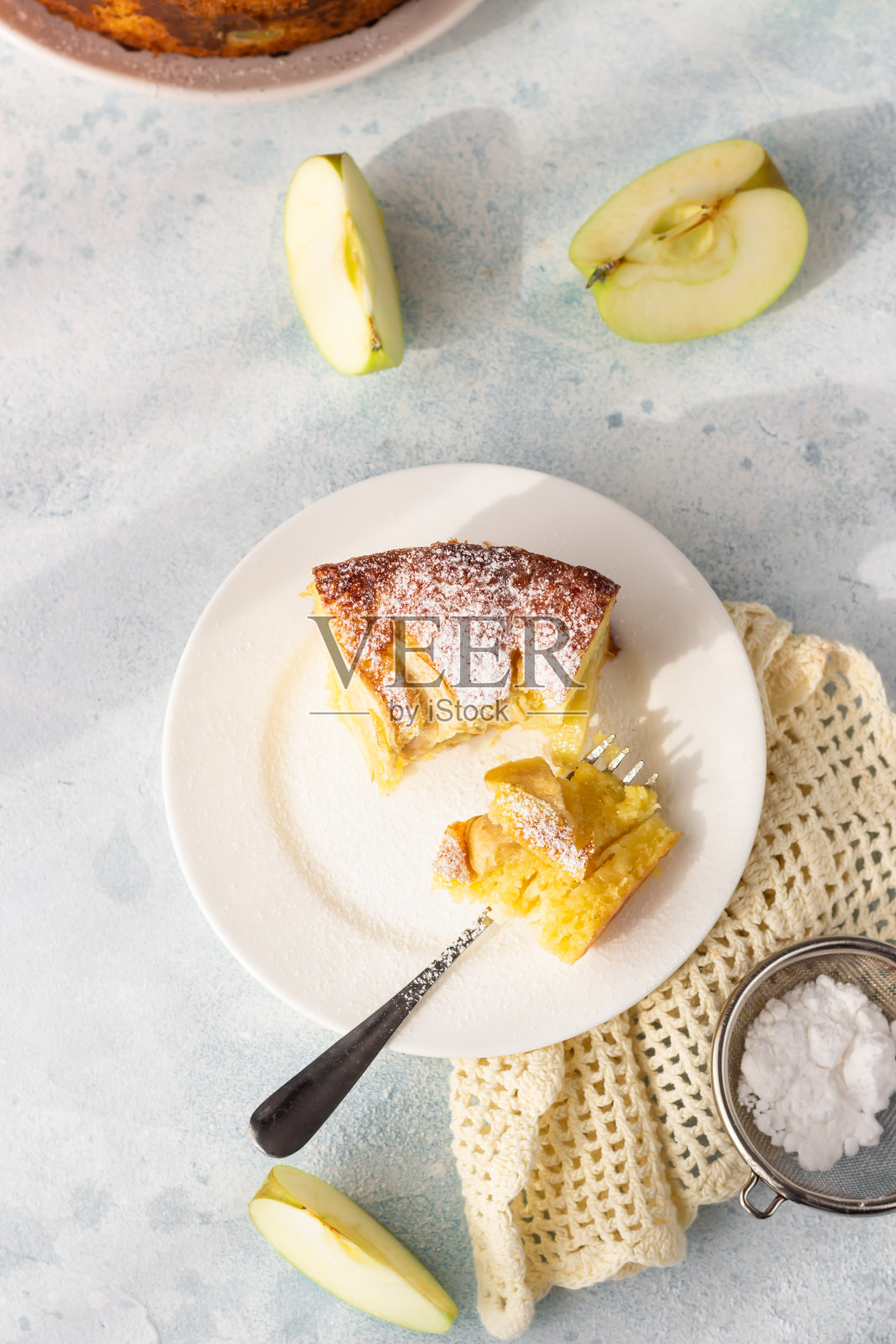 一块夏洛特和苹果。用糖粉装饰的美味苹果派或海绵蛋糕。早晨大气的灯光,时尚的柔和阴影,选择性聚焦。前视图。照片摄影图片