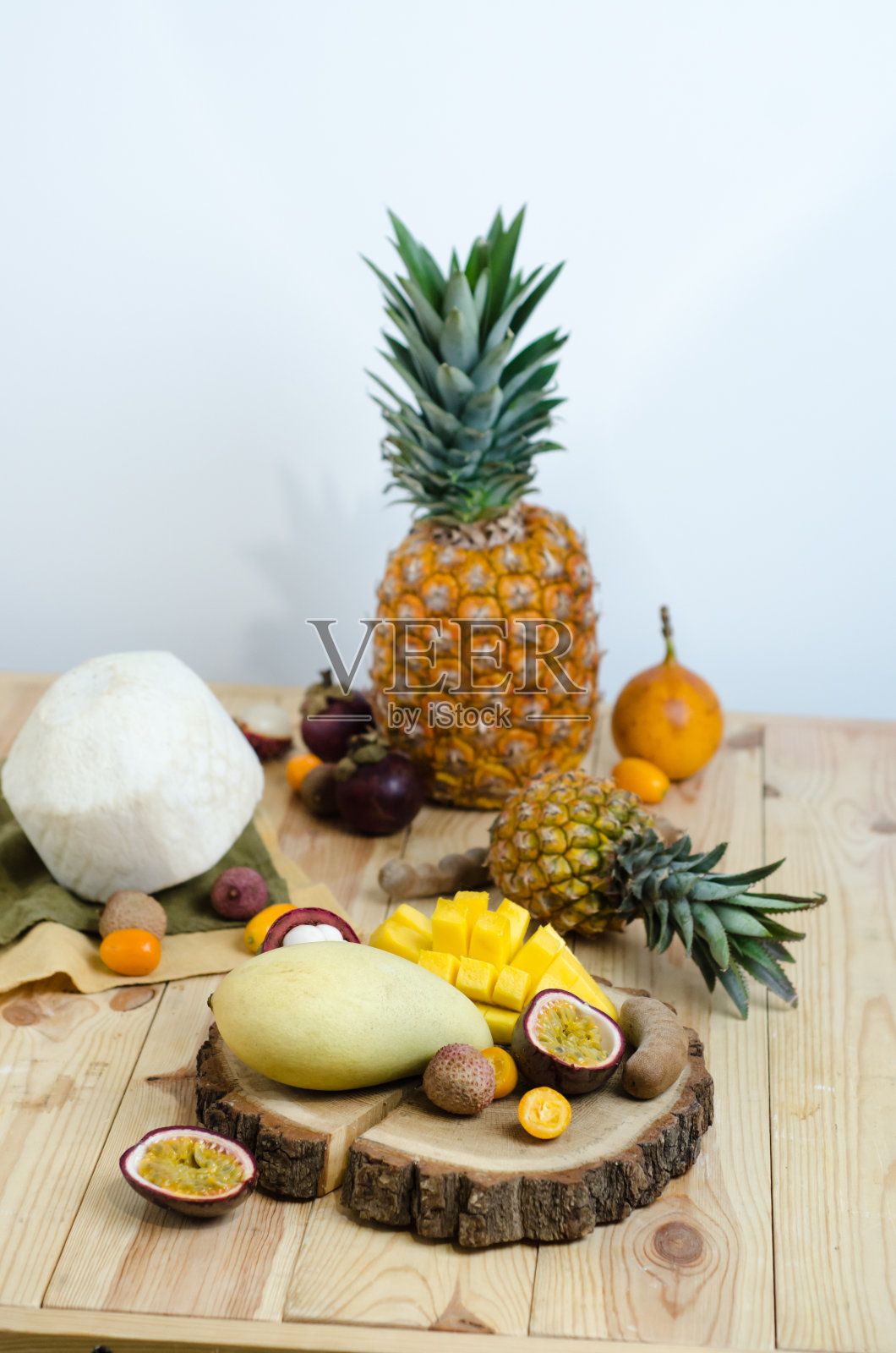 木桌上放着各种热带水果。照片摄影图片