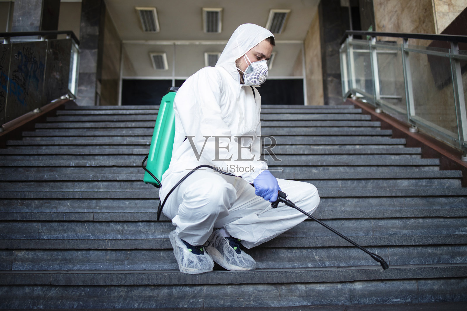 身穿白色防护服的男子对公共区域进行消毒,防止高传染性冠状病毒传播照片摄影图片