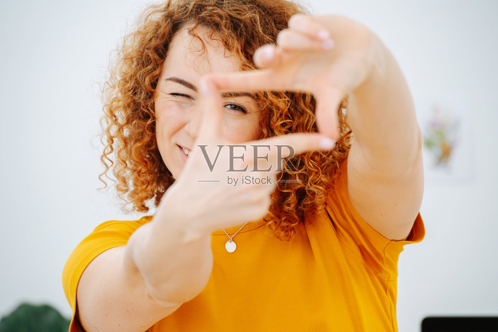 女孩用手指做了一个框架,然后透过框架往外看照片摄影图片