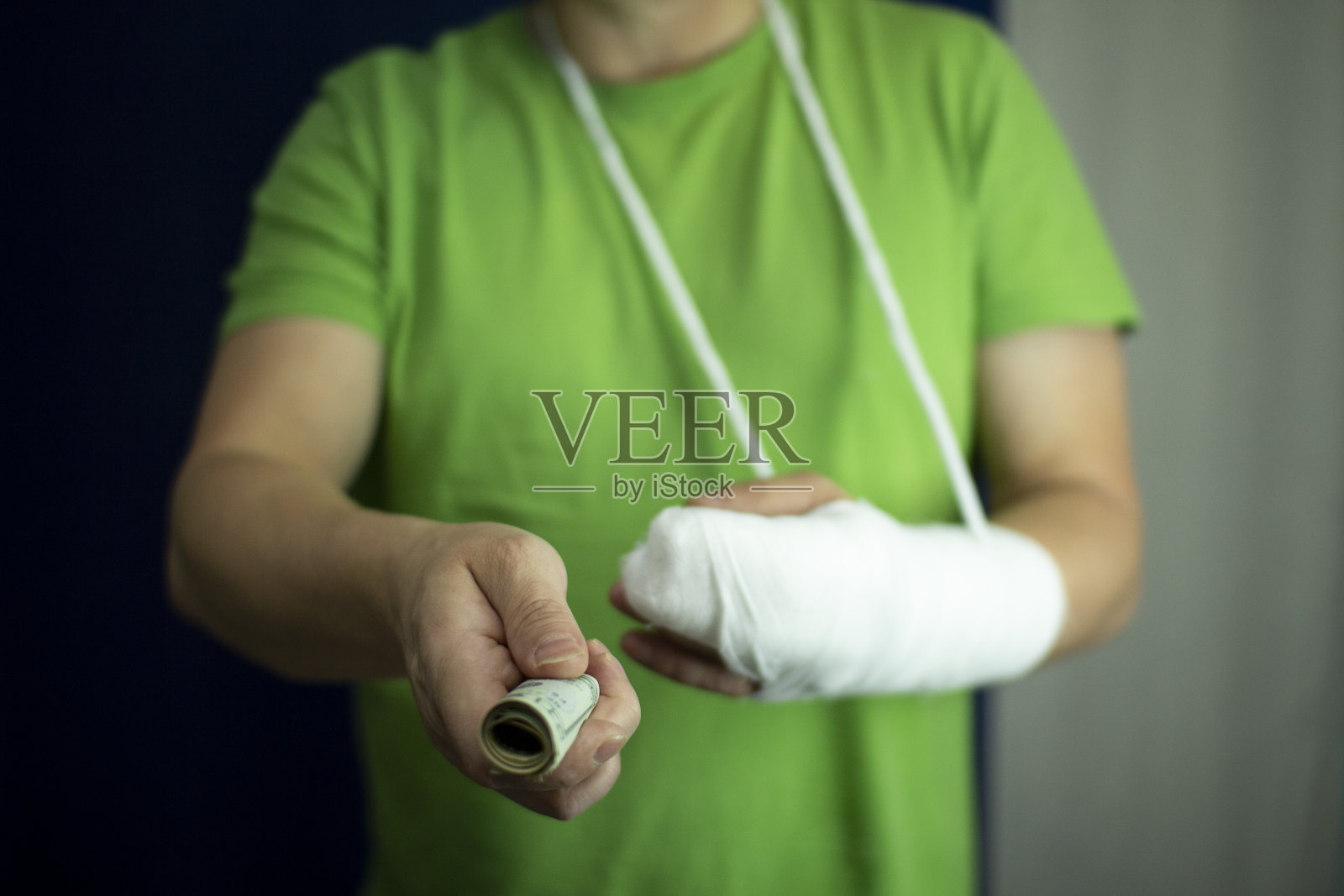 一个打着石膏的手臂上的男人从医院的紧急医疗护理费用中数出钱来。照片摄影图片