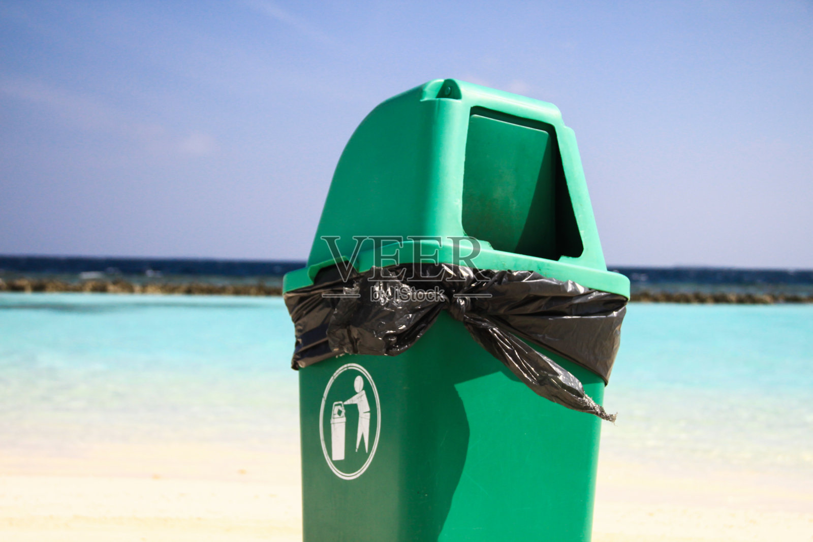 回收废物后,在干净的热带沙滩上的绿色塑料垃圾桶照片摄影图片