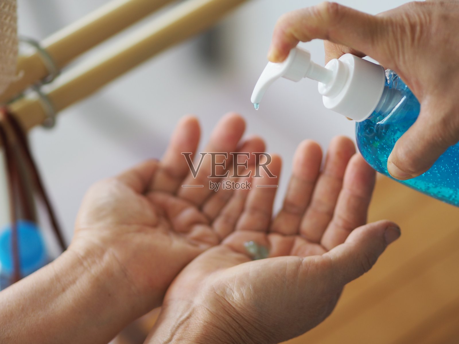 一名妇女正在将70%酒精和明胶混合的凝胶泵放在手指头上,以预防细菌保护结肠病毒,冠状病毒,洗手液照片摄影图片