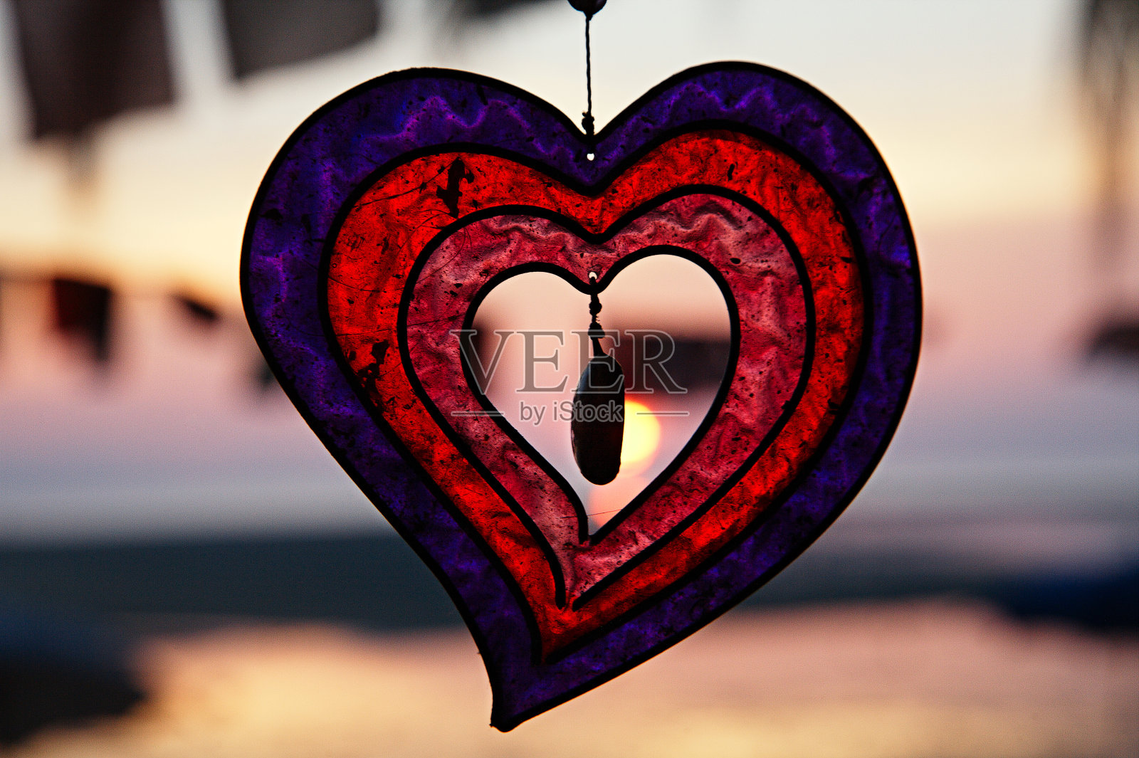 海上日落背景上的玻璃红心。浪漫的心跳。照片摄影图片