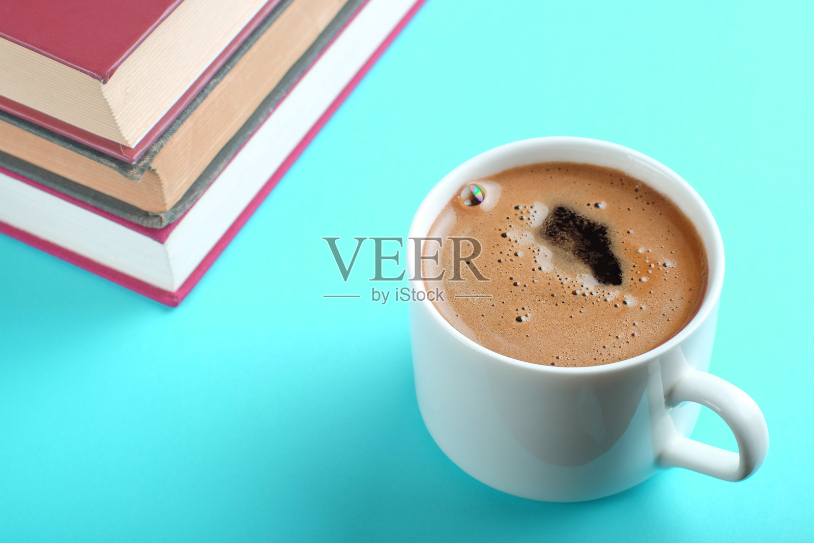 一杯热咖啡和水蓝背景的书。呆在家里的概念。自我隔离/自我教育理念。照片摄影图片