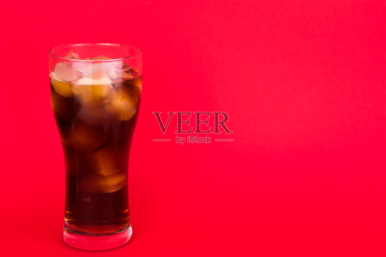 红色背景加冰的可乐杯。副本的空间。照片摄影图片