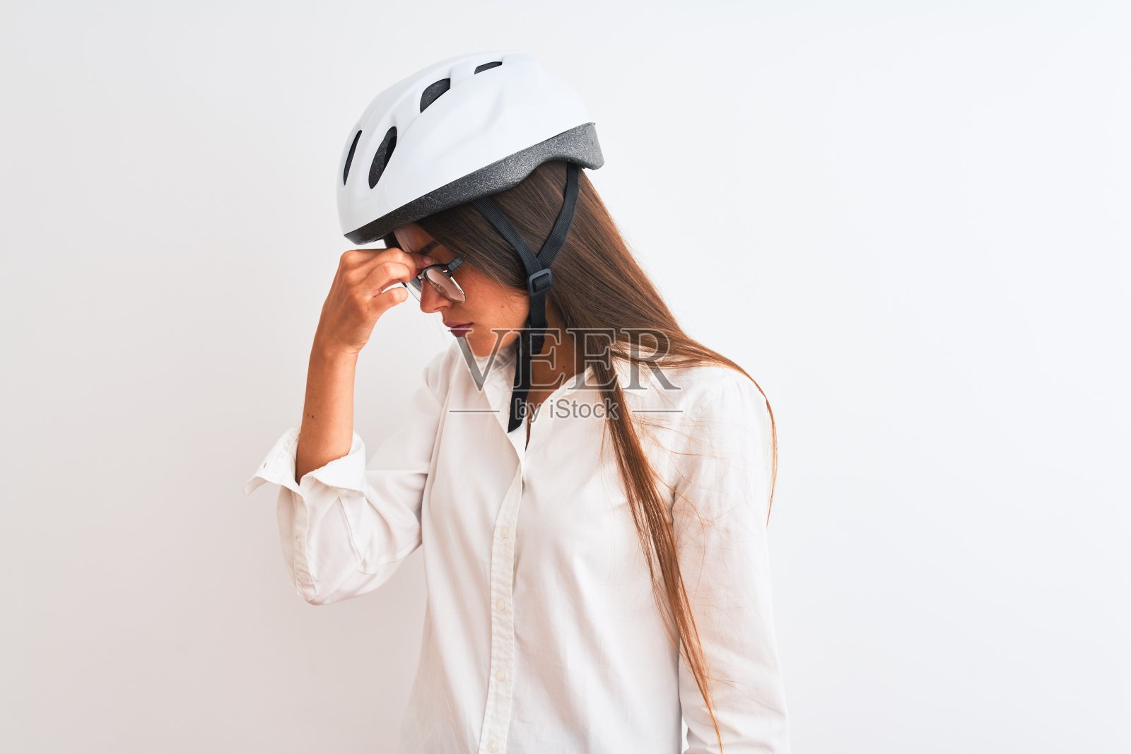 美丽的女商人戴眼镜和自行车头盔在孤立的白色背景疲劳摩擦鼻子和眼睛感觉疲劳和头痛。压力和挫折的概念。照片摄影图片