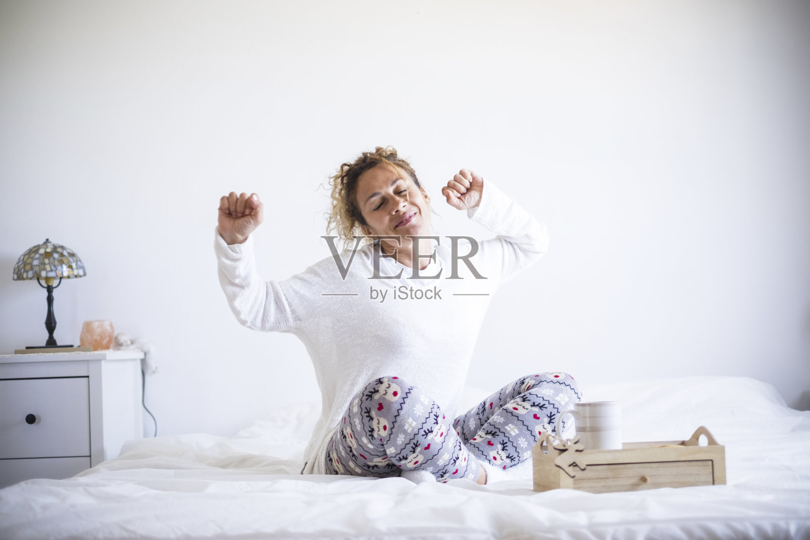 清晨醒来:快乐的白人女性伸展微笑,居家或酒店隔离照片摄影图片