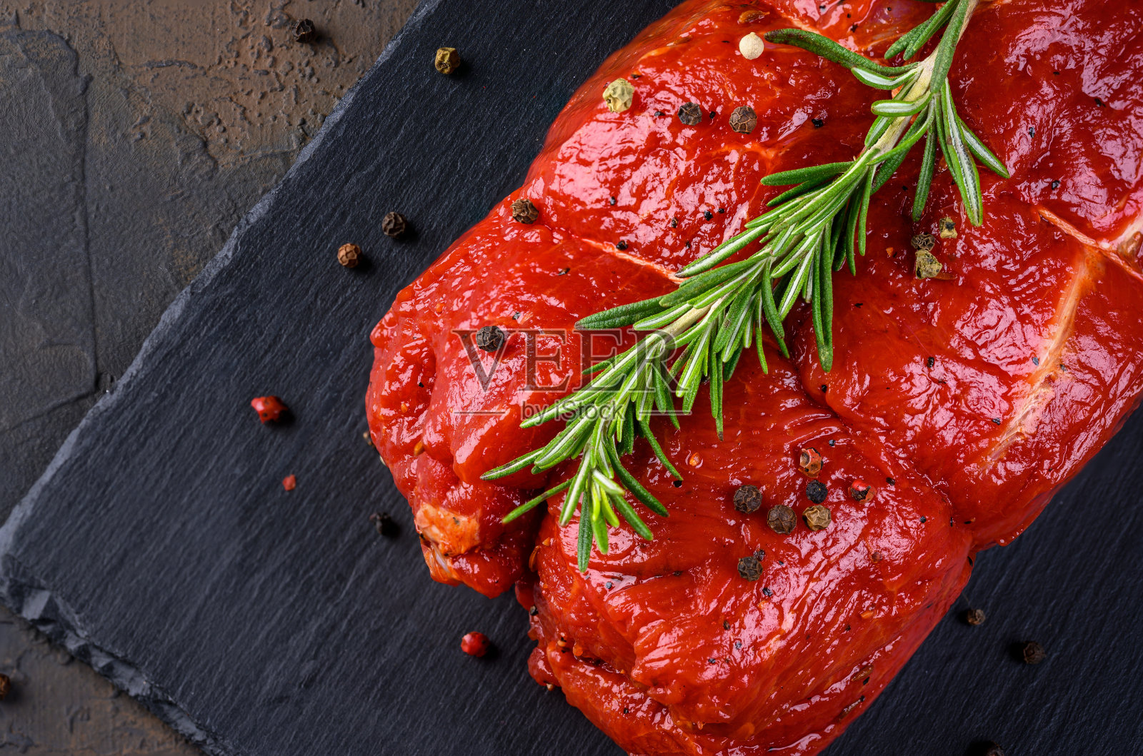 生肉。一大块牛肉排放在石板上,以迷迭香和香料为背景照片摄影图片