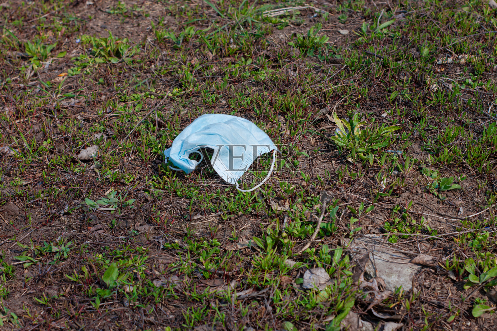 2019冠状病毒病隔离期间,在公园绿地上佩戴医用口罩。具有病毒和疾病风险的危险废物。照片摄影图片