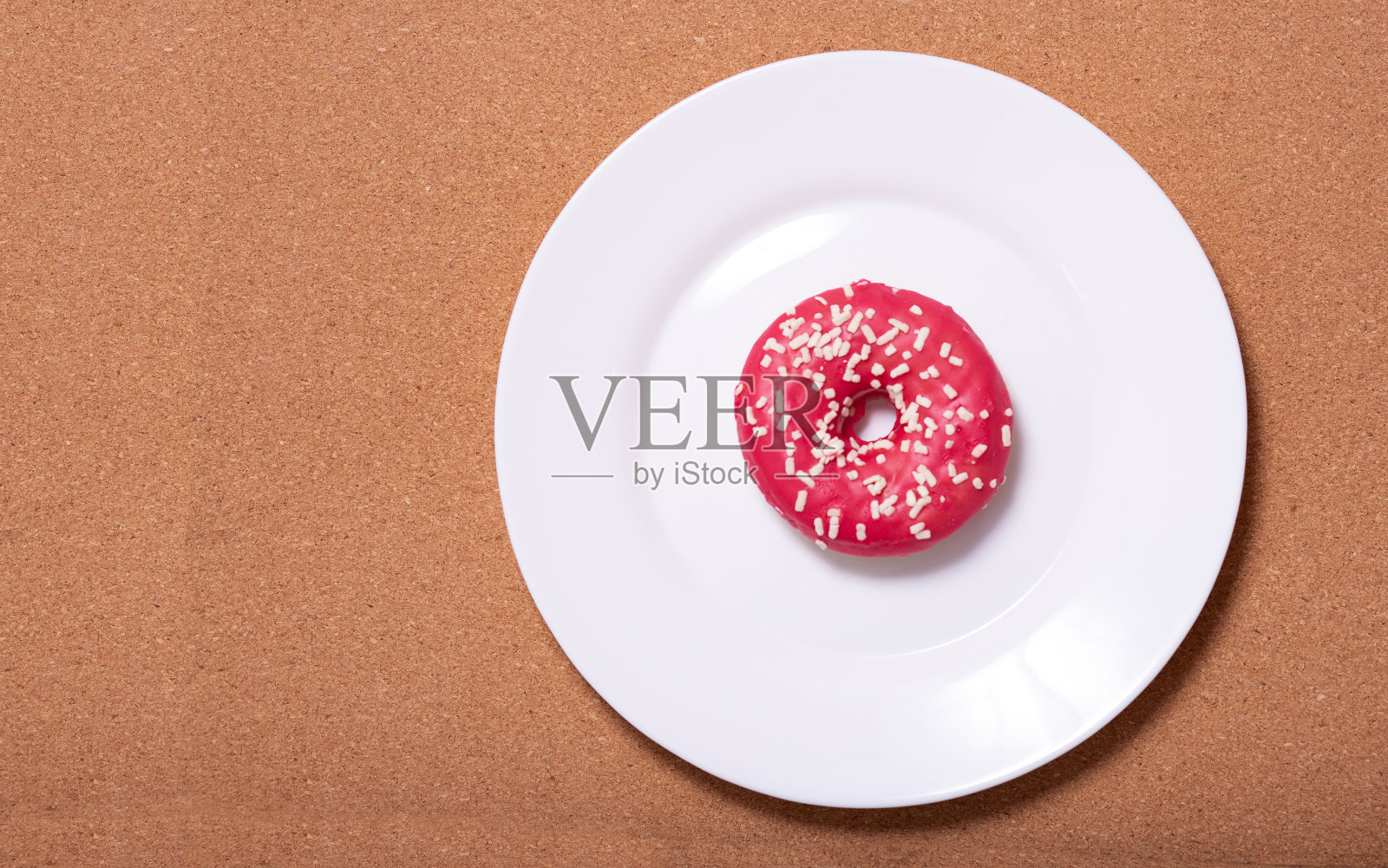 甜甜圈躺在软木背景的白色盘子上,俯视图照片摄影图片