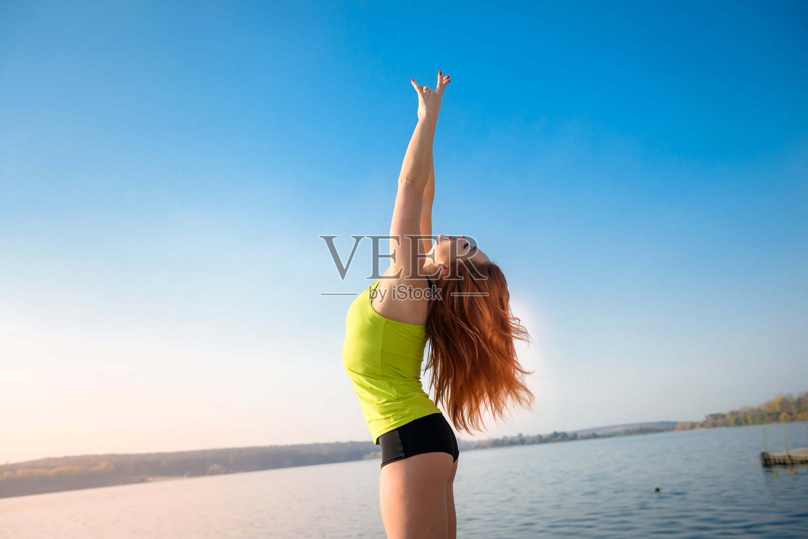 穿着运动服的女孩在湖边晨练后休息。健康美容理念。照片摄影图片