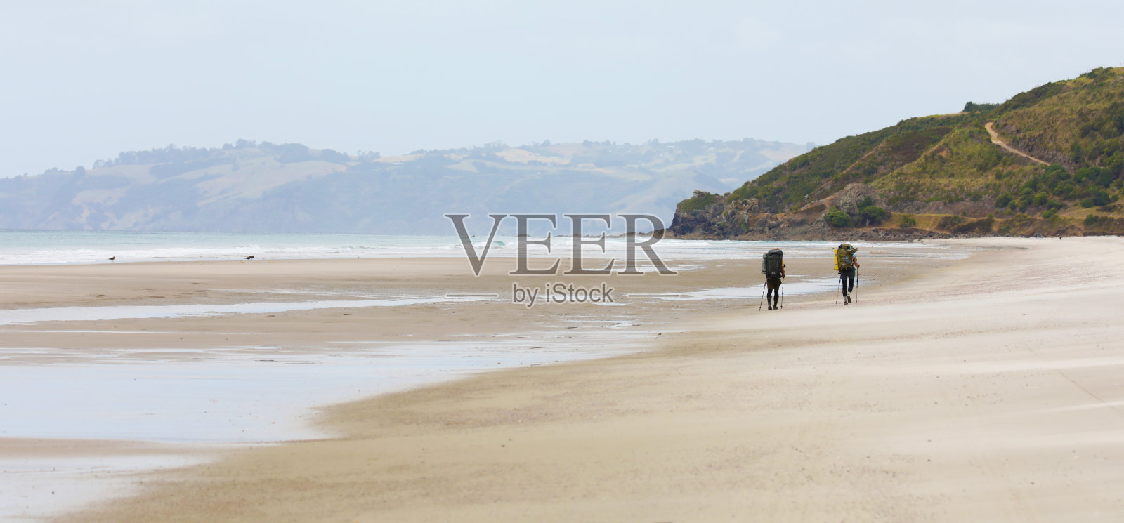 一对徒步旅行者在广阔的新西兰海滩上照片摄影图片