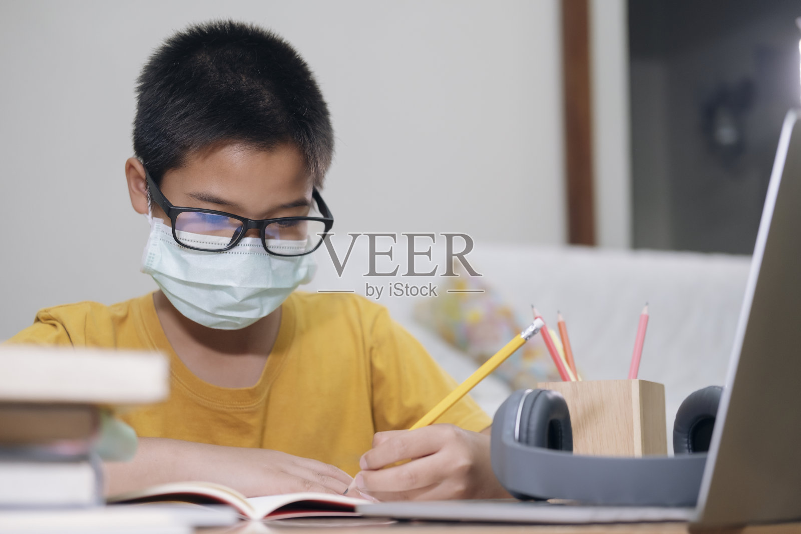 男孩戴着口罩在家上网课照片摄影图片
