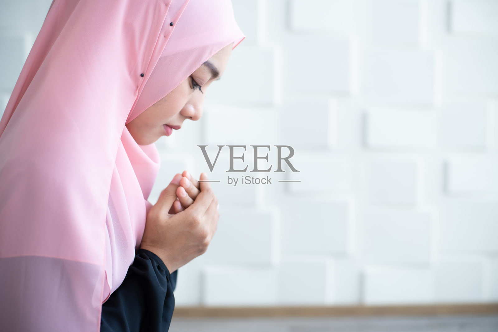 亚洲年轻美丽的穆斯林女学生在室内的地毯上祈祷照片摄影图片