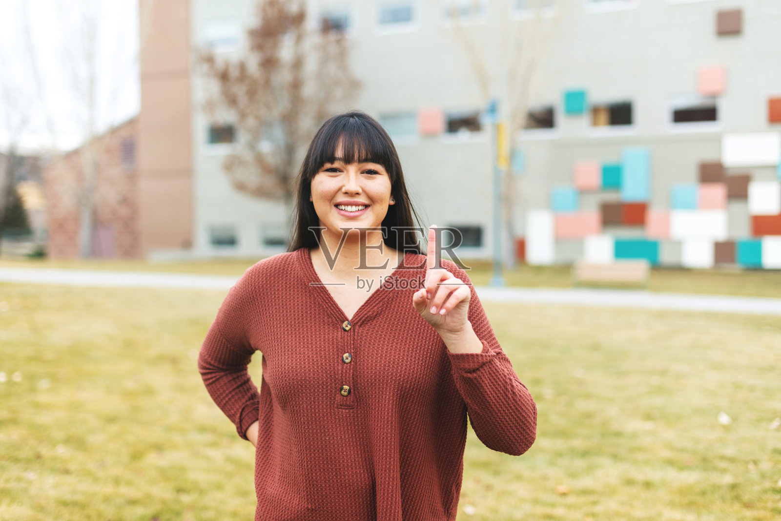 西班牙裔女大学生举起食指指一照片摄影图片