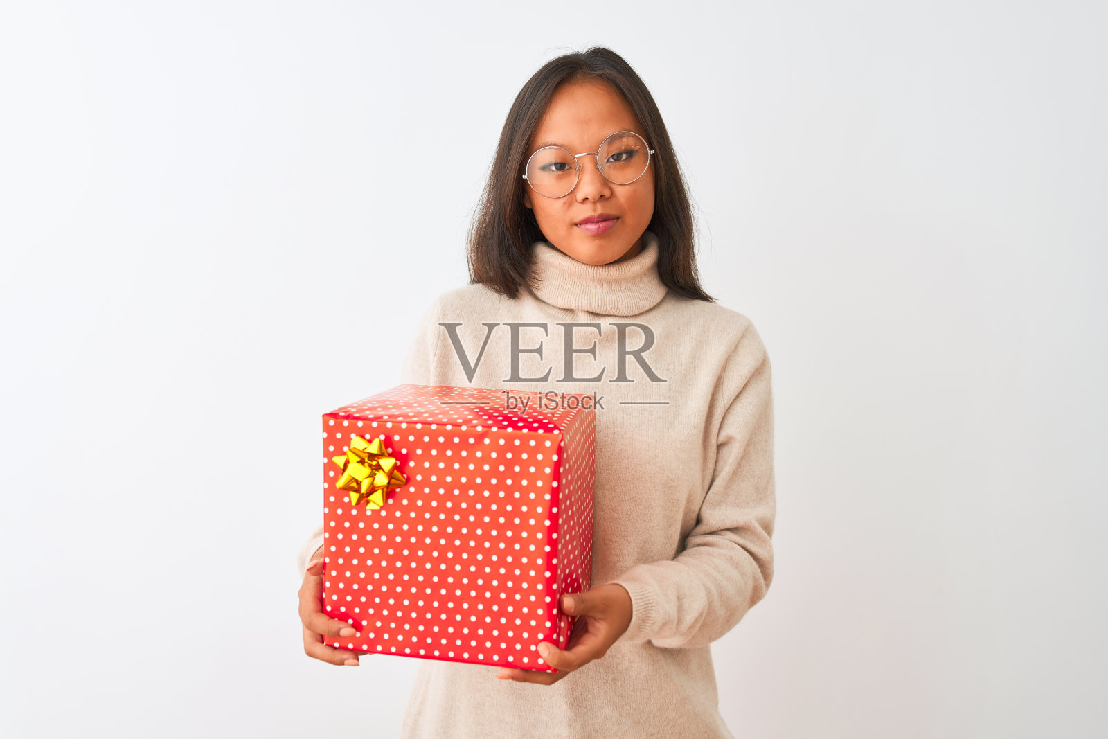 年轻的中国女子戴着眼镜,拿着生日礼物在孤立的白色背景下,聪明的脸上充满自信的表情,思考严肃照片摄影图片