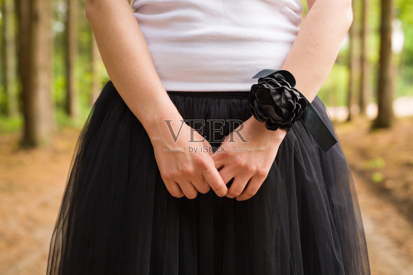 一个年轻的女孩穿着白色背心和黑色蓬松的裙子在森林外面。黑色的花腕带。庆典,晚会。伴娘。的婚礼。照片摄影图片