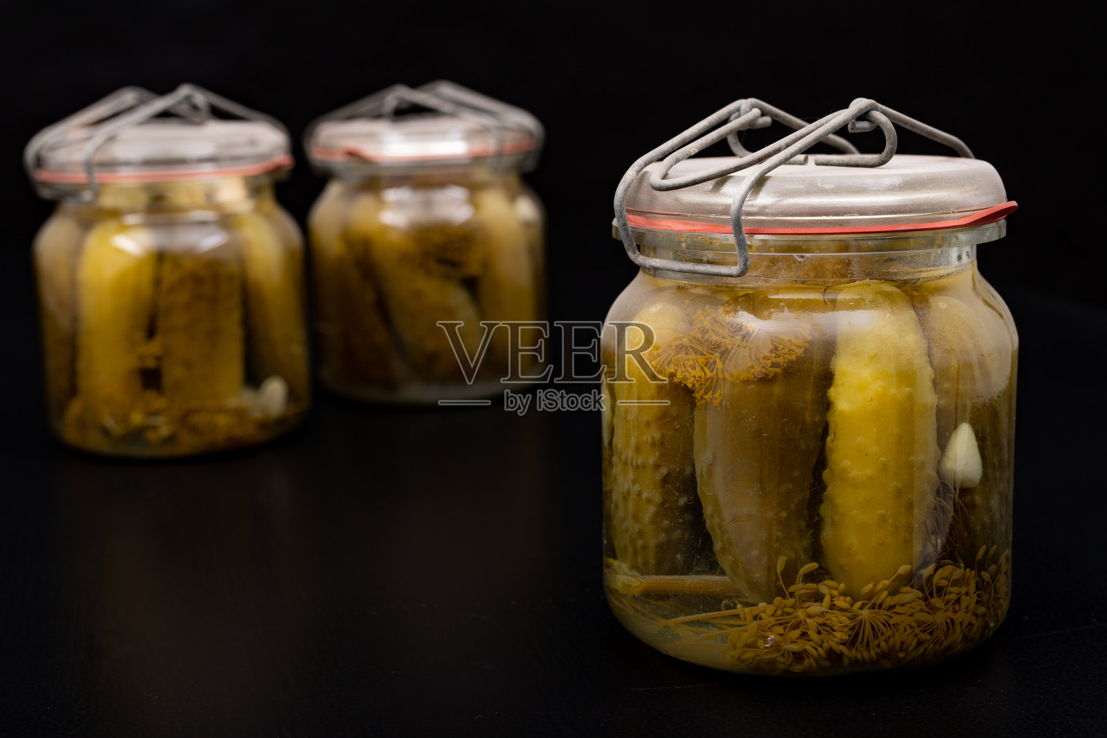 一罐腌黄瓜。自家花园里的美味迫击炮。黑暗的背景。照片摄影图片