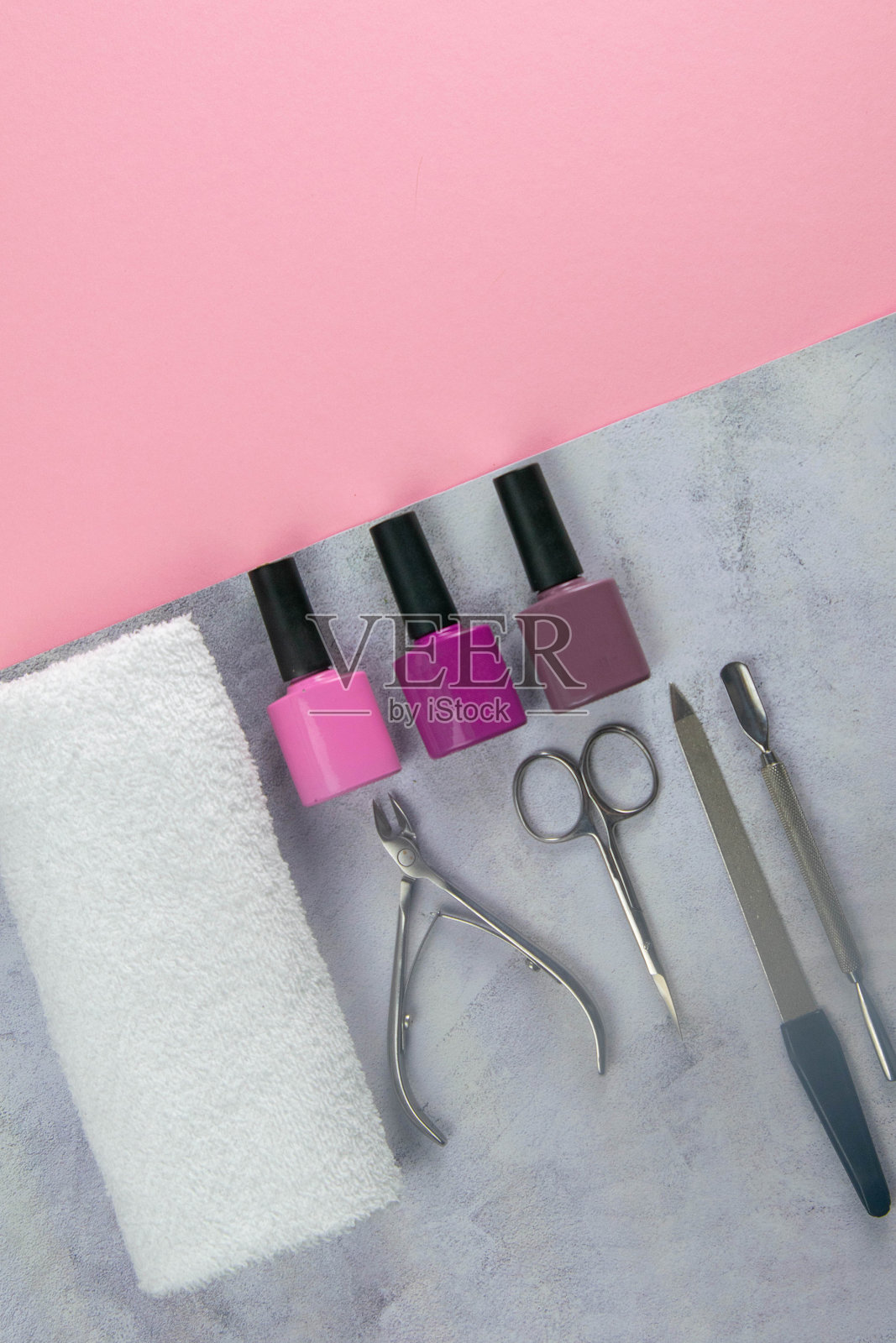一套用于修指甲和修脚的化妆工具。凝胶抛光,美甲剪刀,角质层,锯,磨粉机和毛巾站在混凝土粉红色的背景上。顶部视野与清晰的空间照片摄影图片