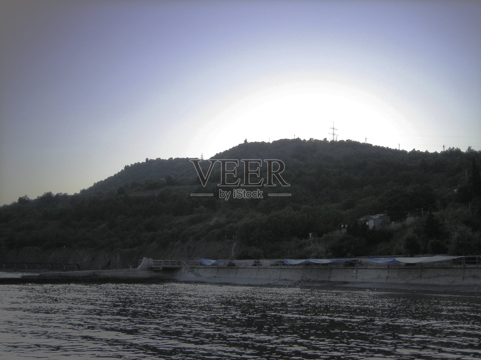 夕阳西下时,古老的石堤在多岩石的海滩上。照片摄影图片