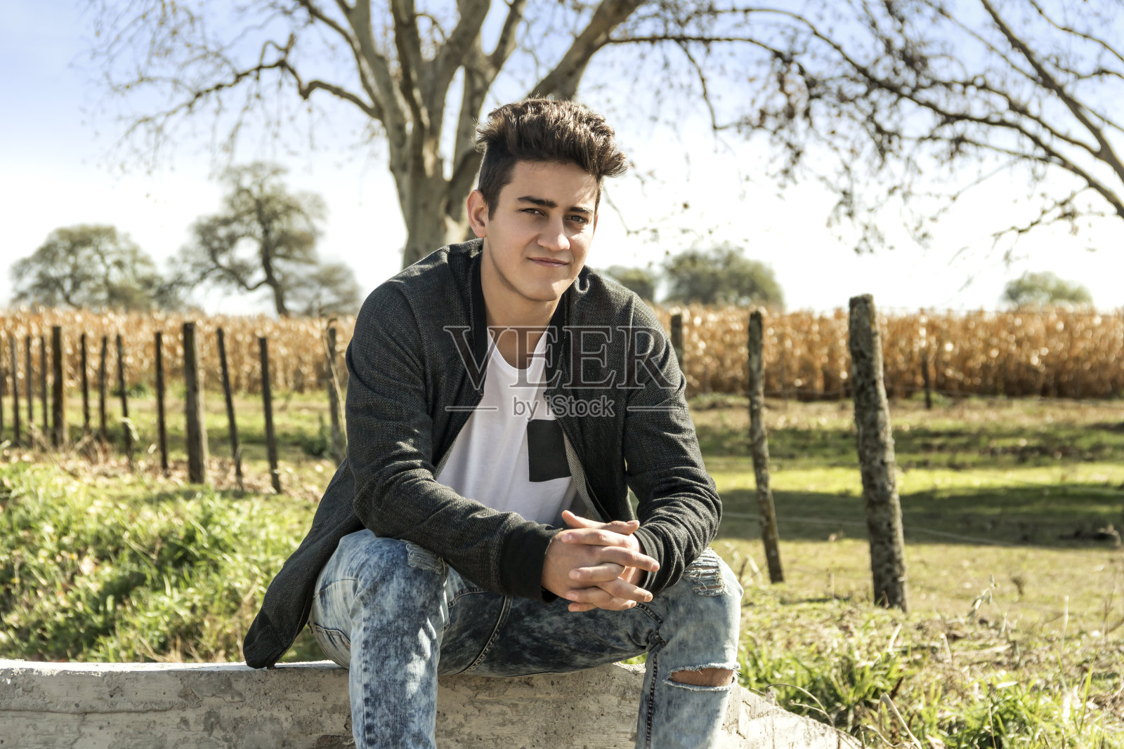 英俊的年轻人休息在一个农业地区与种植玉米的背景。阿根廷科尔多瓦。照片摄影图片