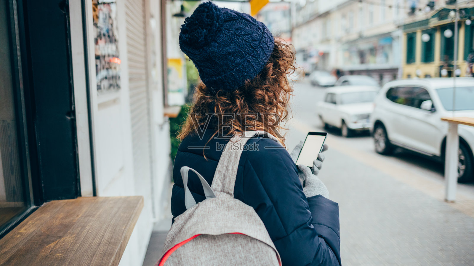 后视图年轻女子戴着帽子站在城市街道上照片摄影图片