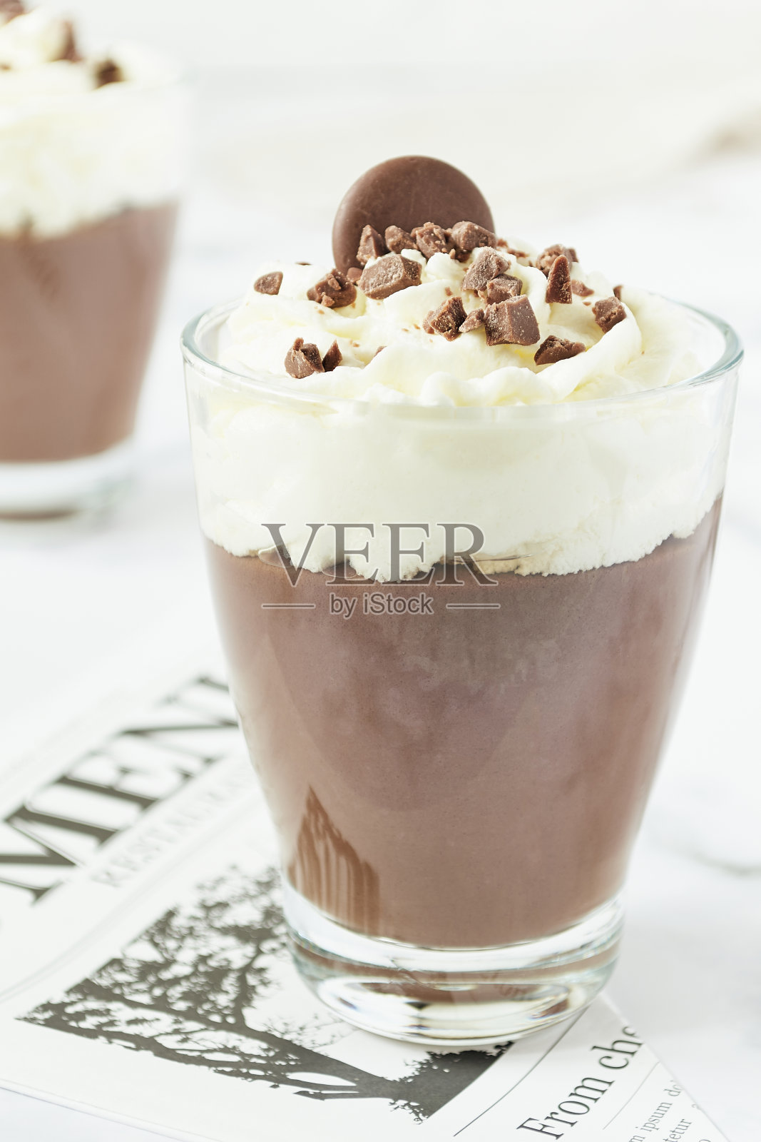 餐厅菜单上的巧克力慕斯和奶油杯。照片摄影图片