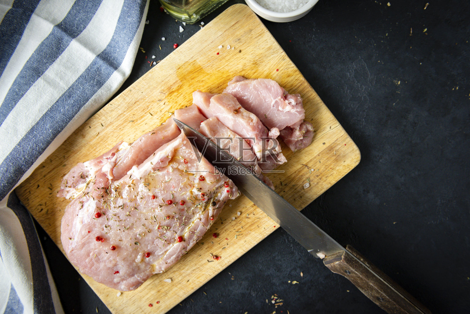 生肉,猪肉里脊与香料在砧板上,刀,毛巾在一个黑色的背景,俯视图照片摄影图片