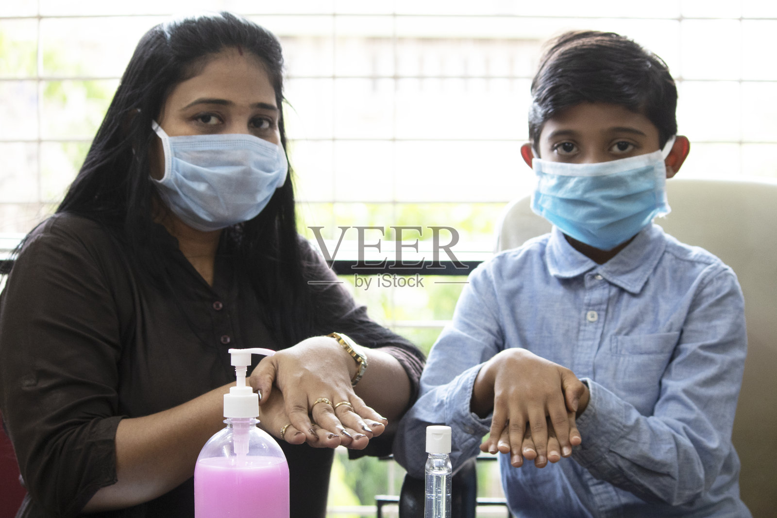 母亲和儿子摩擦消毒剂清洁和消毒双手照片摄影图片