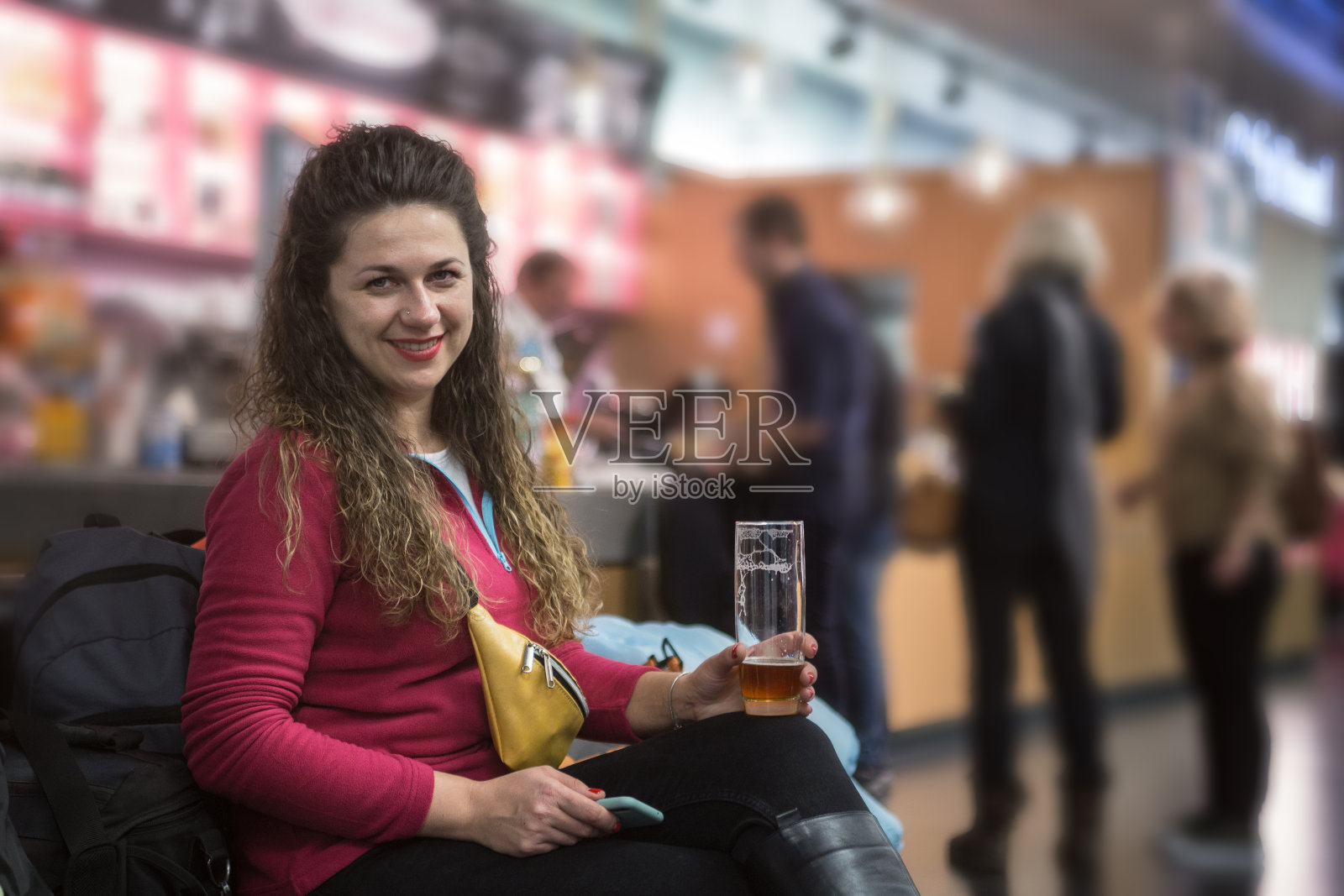 一个女人坐在机场的咖啡馆里喝啤酒。照片摄影图片