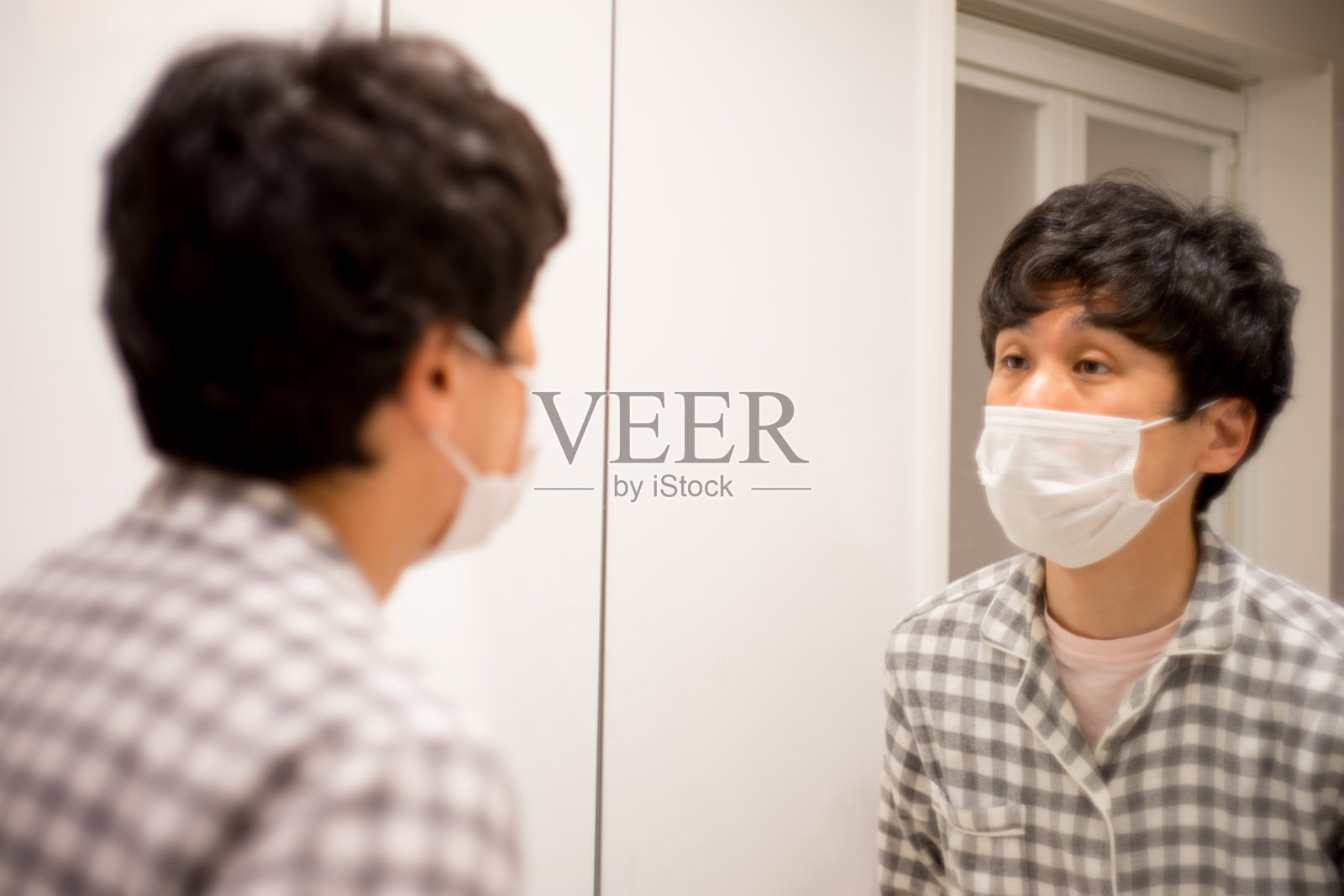 戴着口罩的日本男人在洗手间照镜子照片摄影图片