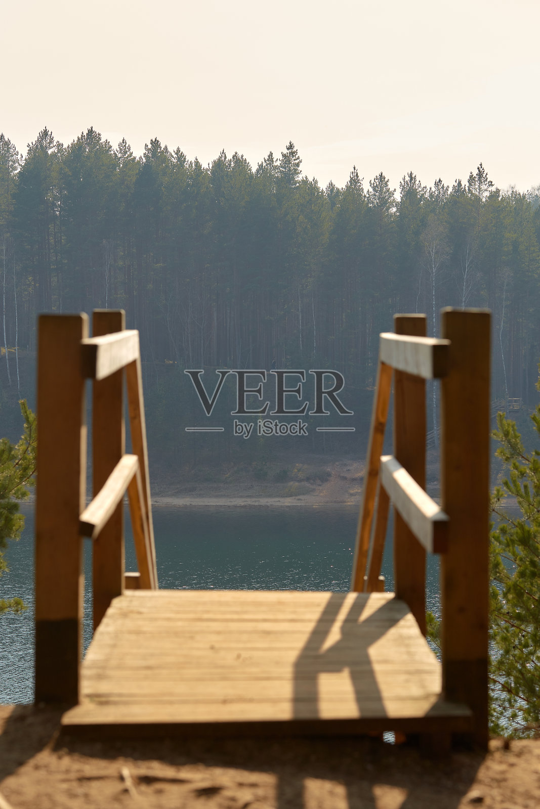 木制平台向下延伸到湖边,可以看到森林的景色照片摄影图片