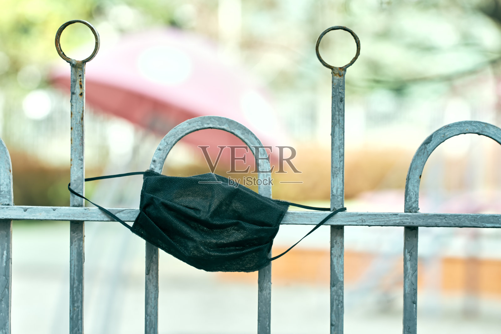 一个空幼儿园的围栏上挂着黑色医用口罩。新型冠状病毒肺炎照片摄影图片