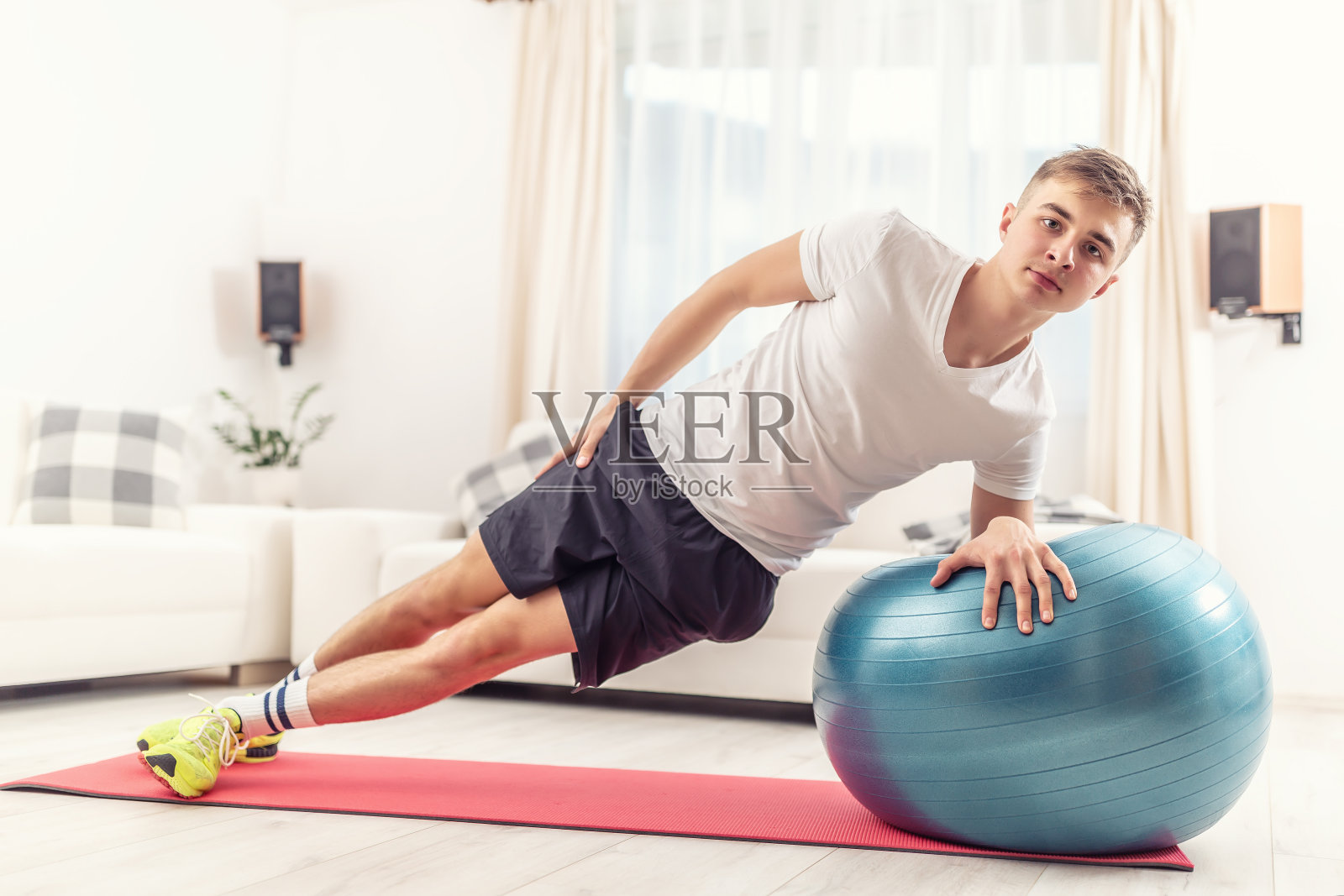 帅气的年轻人在客厅做体重锻炼,肘部保持侧平板姿势,后腿向前伸展。照片摄影图片