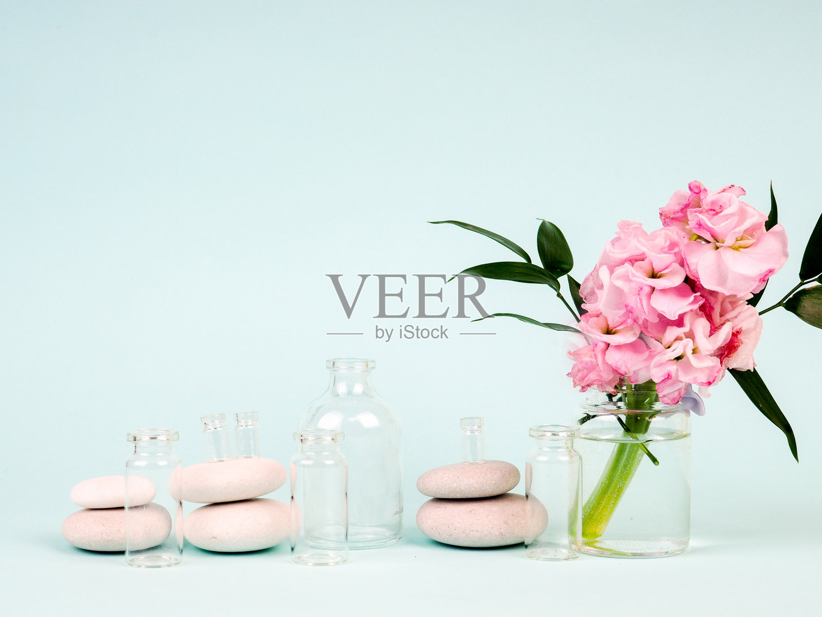 粉红花朵插在花瓶里,旁边是禅宗石,油管,主题水疗和放松照片摄影图片